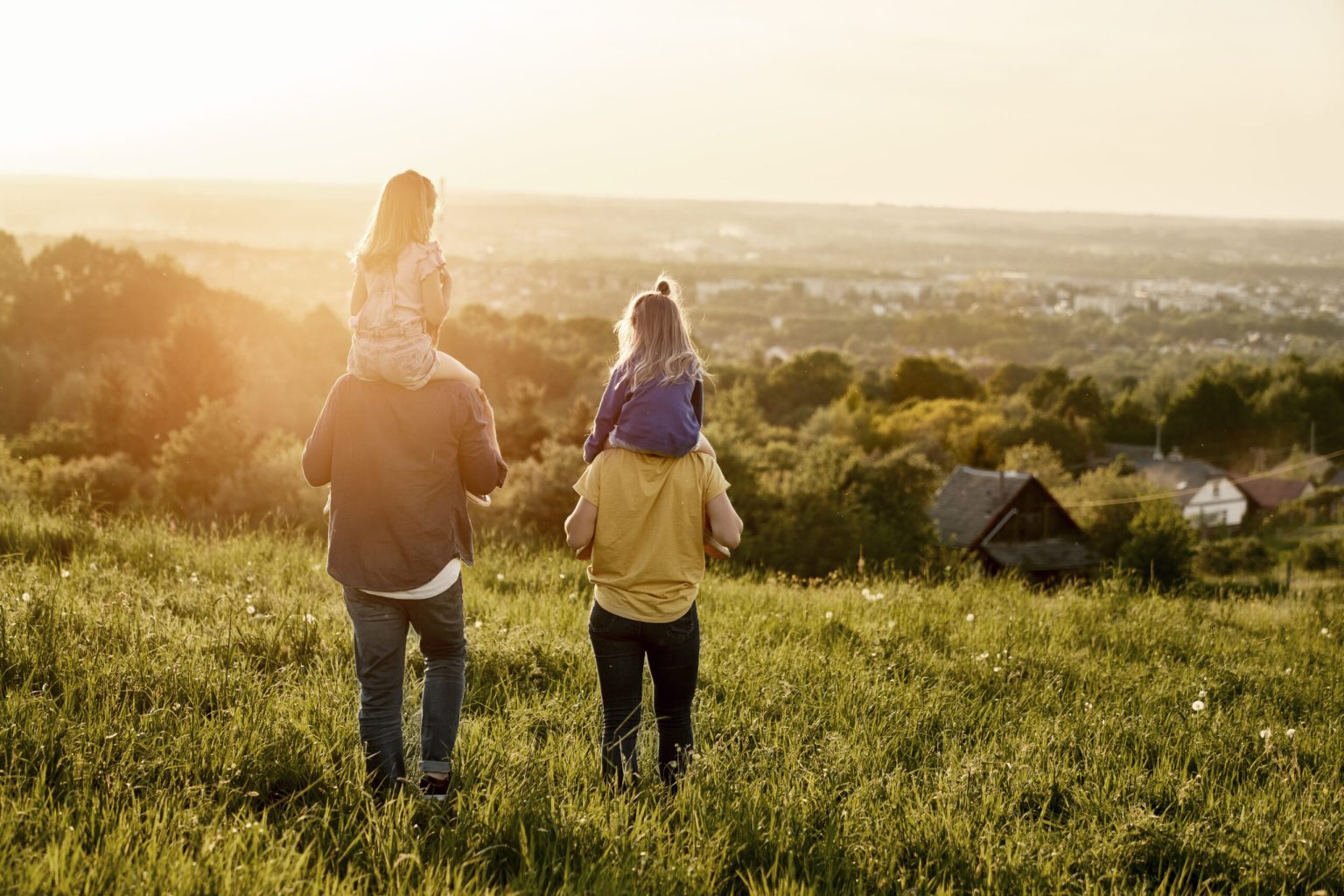 Rear view of family with two daughters walking at the meadow